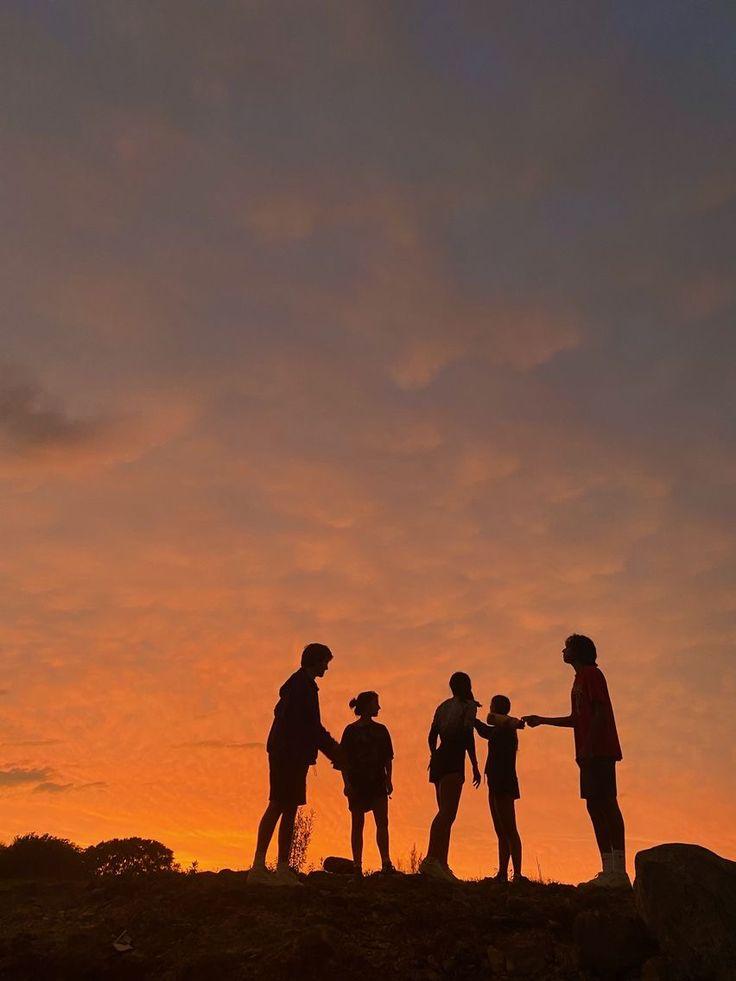 Silhouettes running toward a golden sunset over the ocean